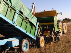 Remolque de agricultor genuino cargando sembradora para labores de agricultura